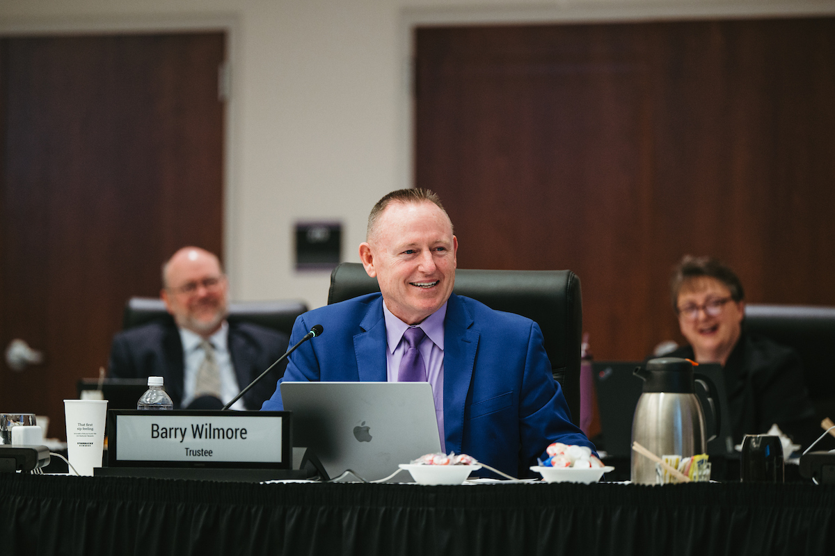 Wilmore in a blue suit seated behind a placard reading 'Barry Wilmore