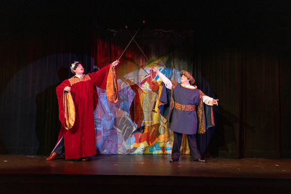 Two students acting out a sword fight on stage.