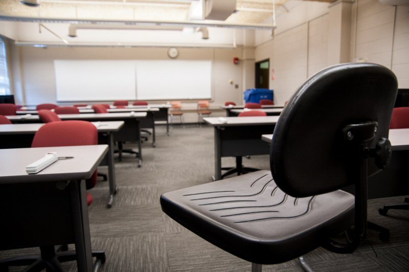 a chair amongst student desks in a classroom