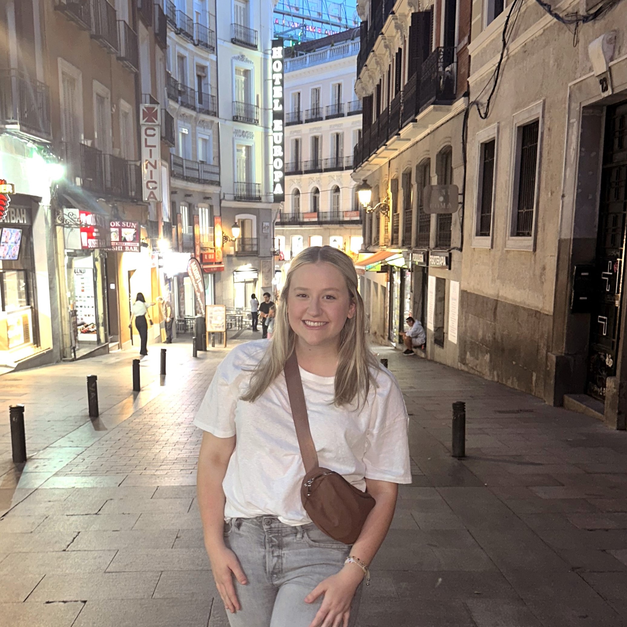 Addison Dorris abroad on a street with neon signs lit up behind her.