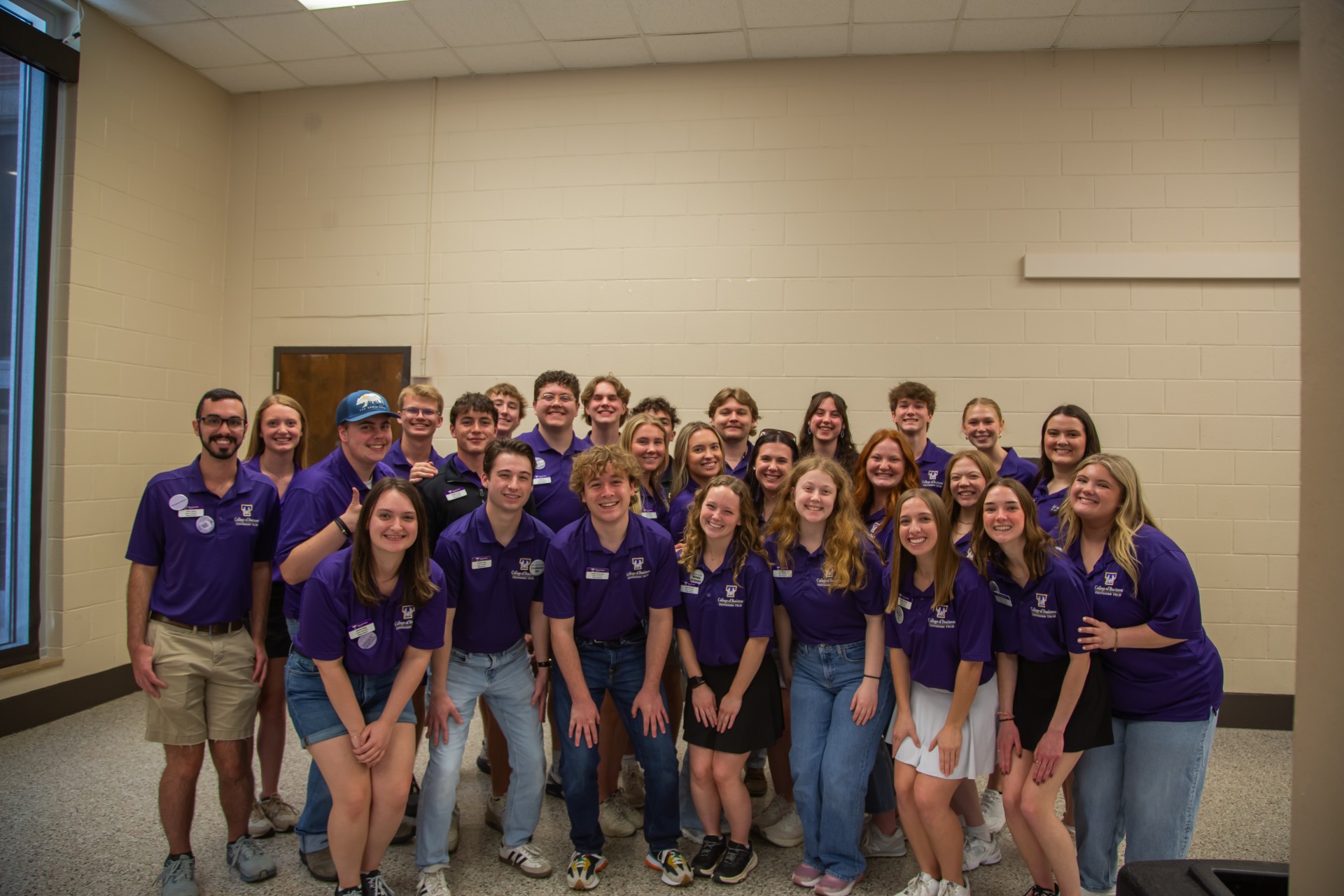 Group photo of approximately 25 Tennessee Tech College of Business student ambassadors standing together indoors, smiling and wearing matching purple College of Business polo shirts.