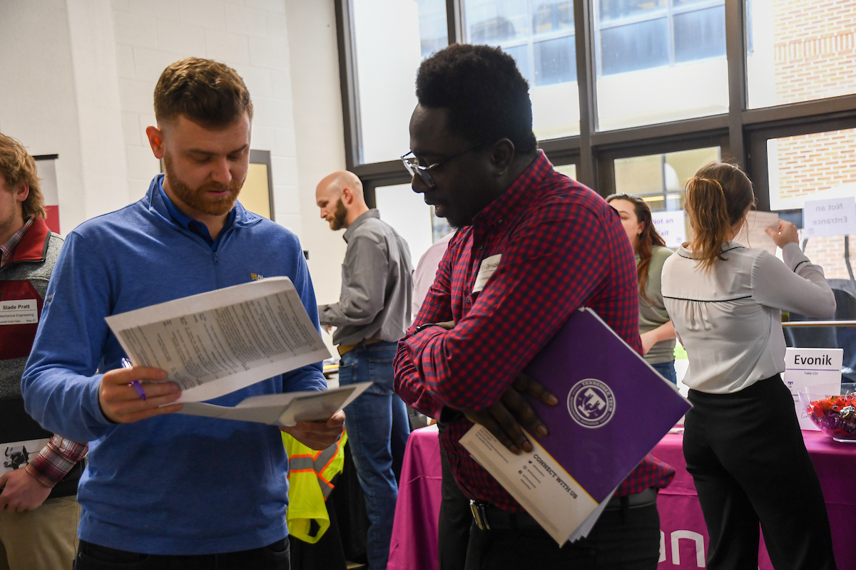 A Tennessee Tech student reviews his resume with a company representative at a career fair. 