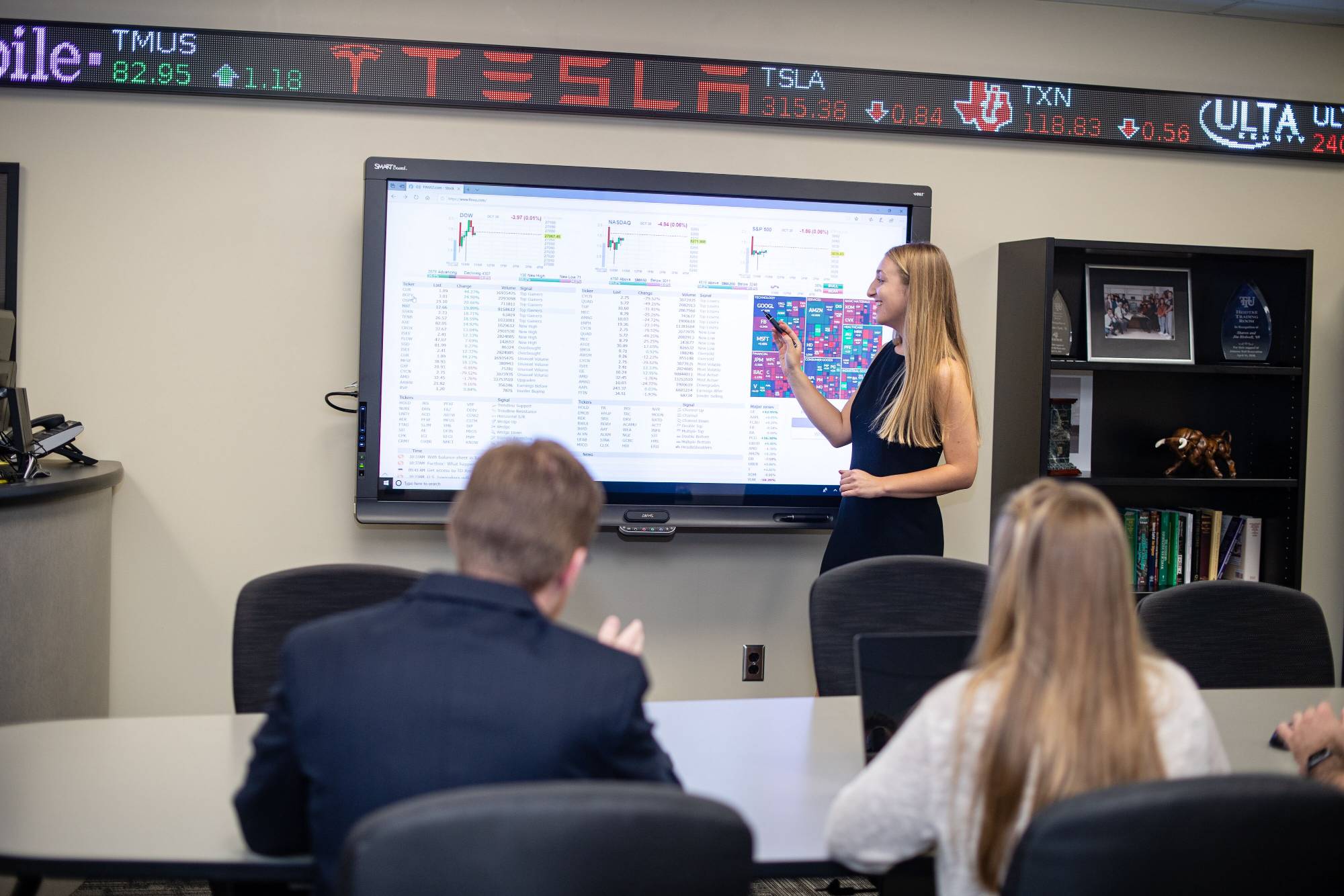 a student presenting in front of a large interactive screen