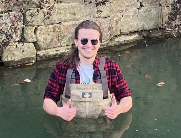 Noah Meyer sranding in river smiling and giving thumbs up