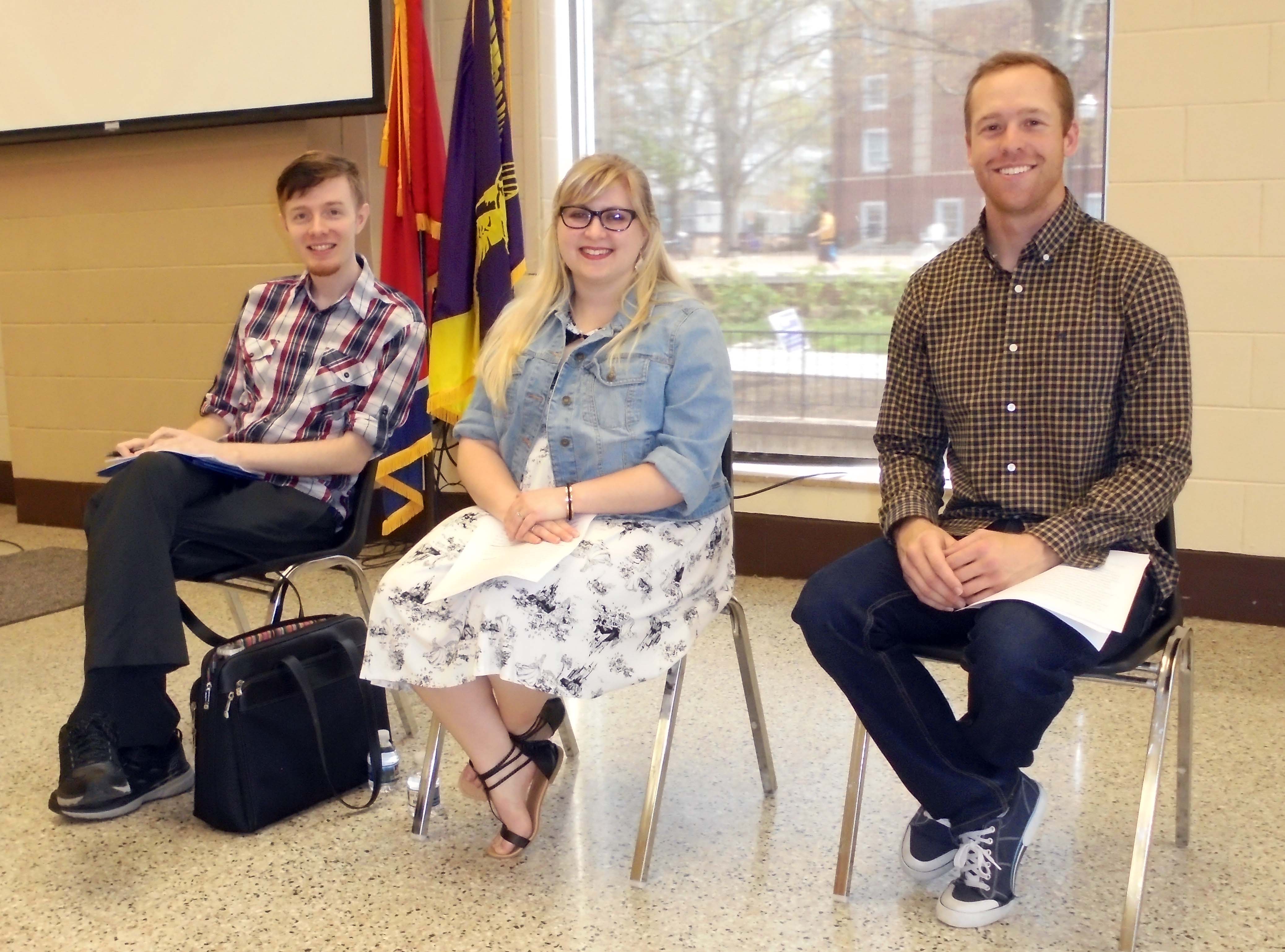 Three students seated and smiling facing the camera