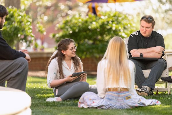 Students sitting outside talking about writing