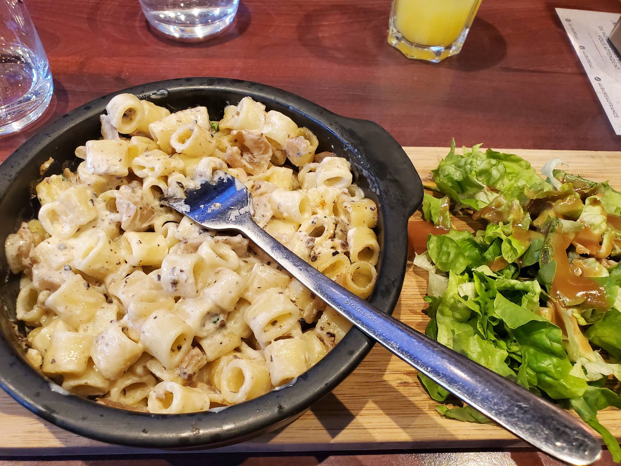 a dish of carbonara pasta with a side salad