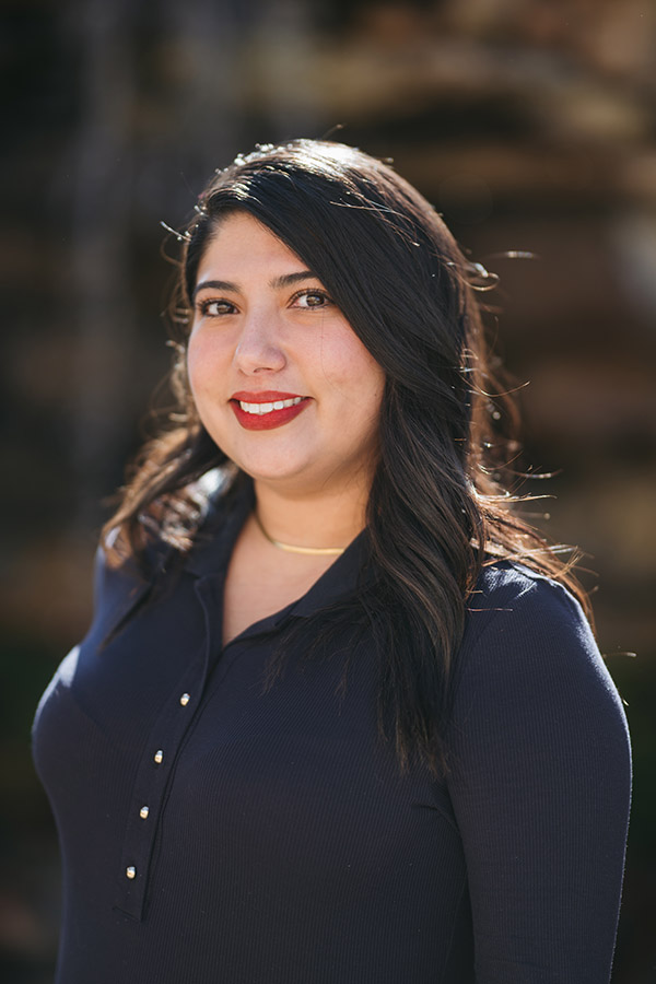 A female with long black hair wearing a black button up shirt.