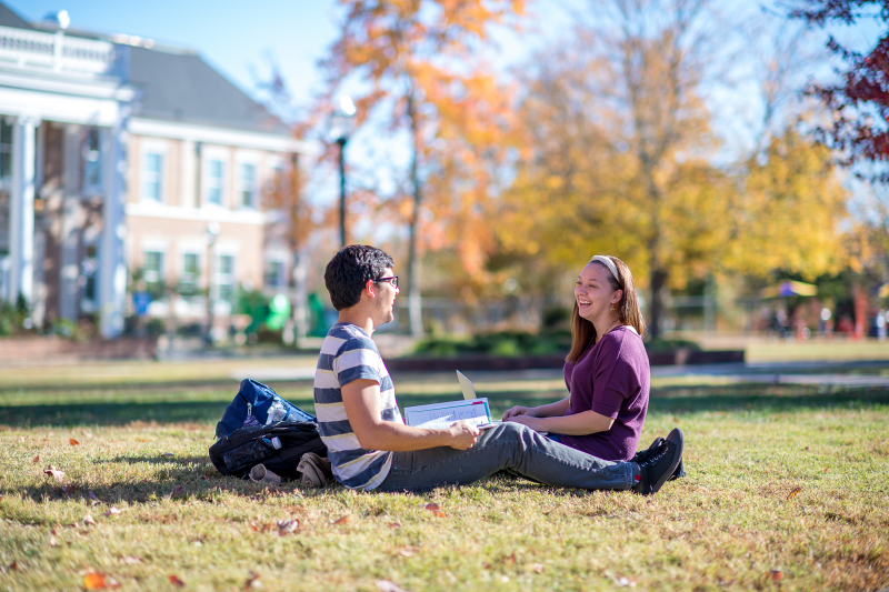 Two students talking while sitted on a green field at Tennessee Tech