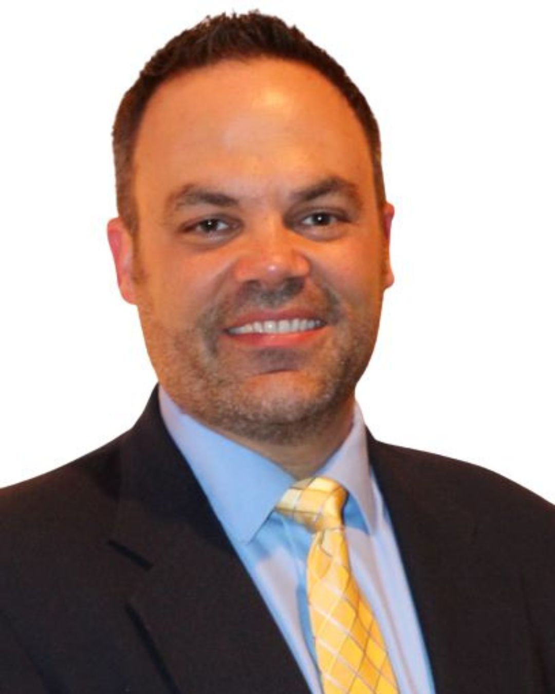 a man in a black blazer, yellow tie and blue dress shirt smiling in front of a white background
