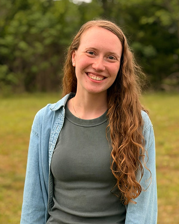 Portrait of Victoria Baldwin posing for the camera in a field of grass.