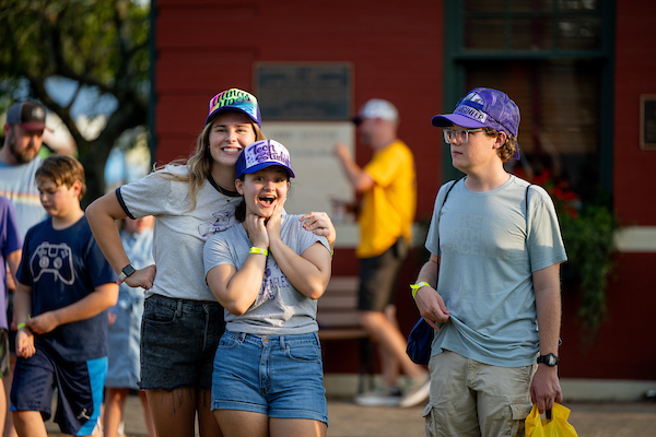 A student giving a large smile to the camera and another student has their hand on their should giving a smile as well.