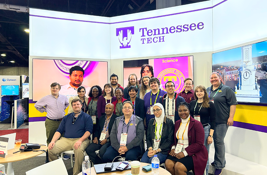 Group of Tn Tech students and faculty gather in front of Tn Tech booth at annual SC24 conference.