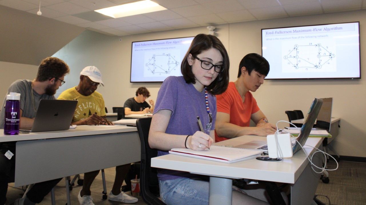 Computer science students take notes in a classroom.