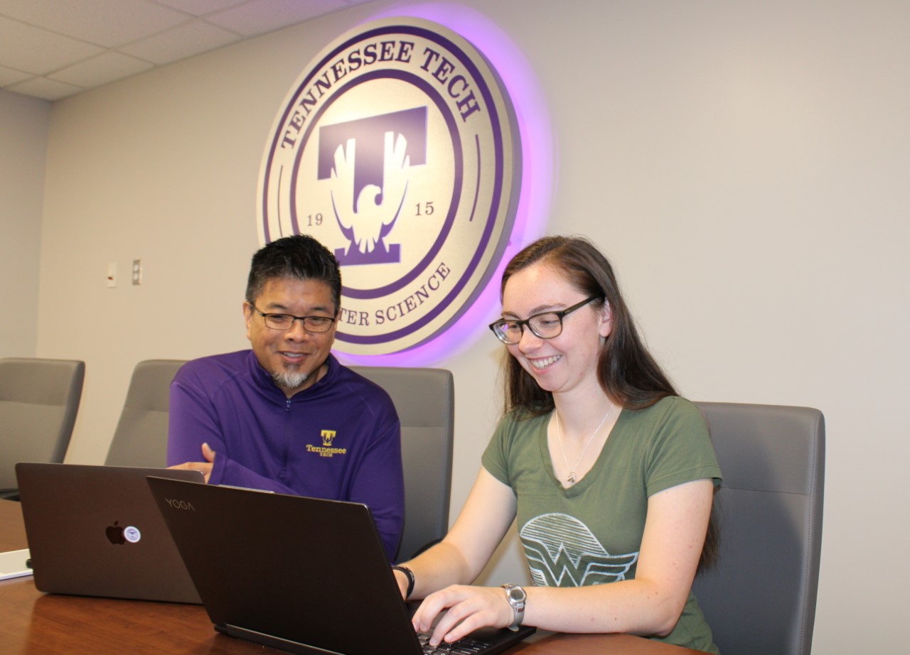 Professor assisting a student at a computer.