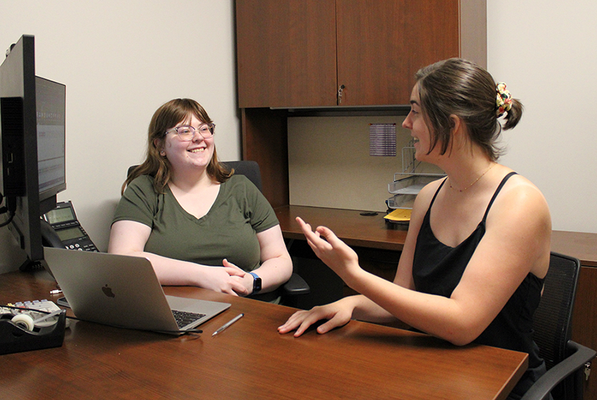 Two students sitting at a desk talking