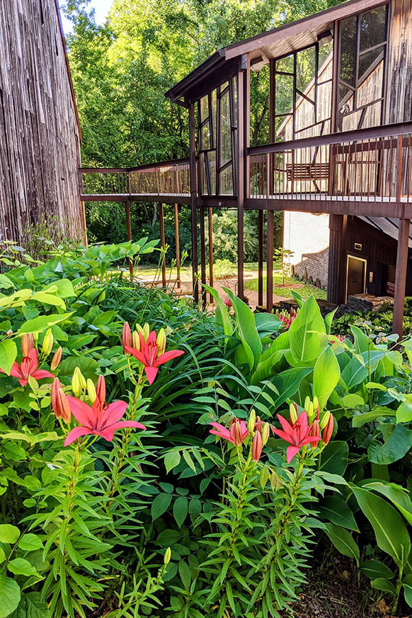 A view of the side of a wooden building with flowers in the foreground.