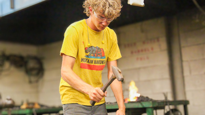 A student hammering in the metal shop class.