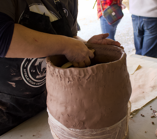 hands building a clay vessel