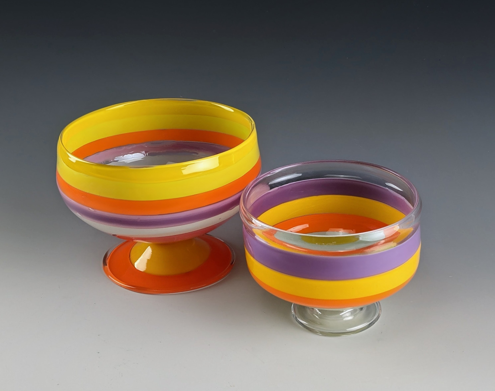 Two glass bowl-like vessels, orange and yellow and purple mainly