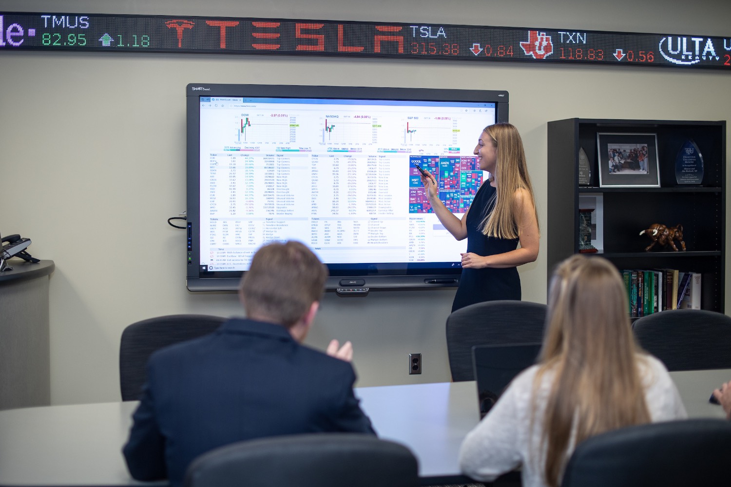 students in College of Business trading room discussing options