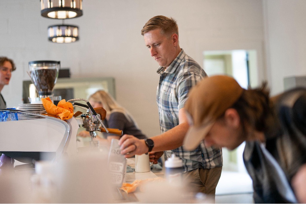 A coffee shop employee preparing a coffee for a customer.