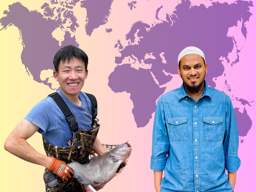 two student standing in front of map smiling. one student is holding a fish