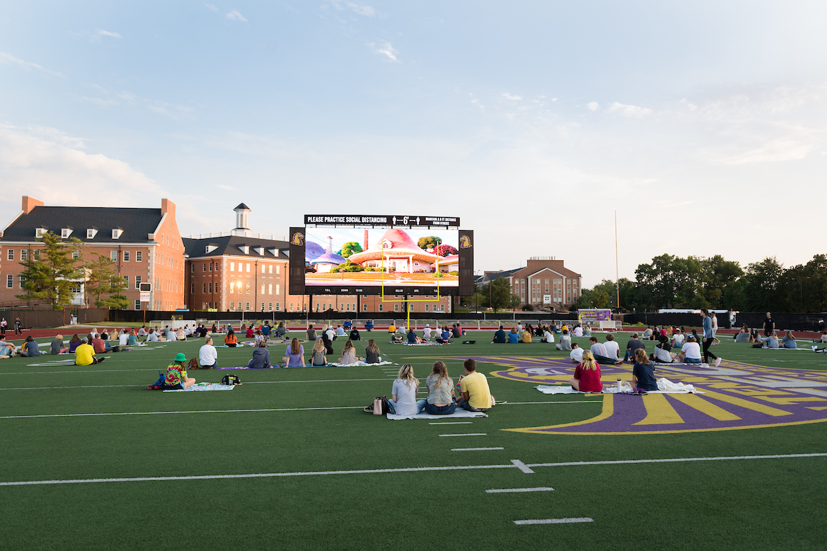 Students watching a movie on the football field.