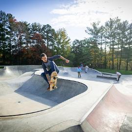 A student performing a skateboard trick in the air at the local skate park. 