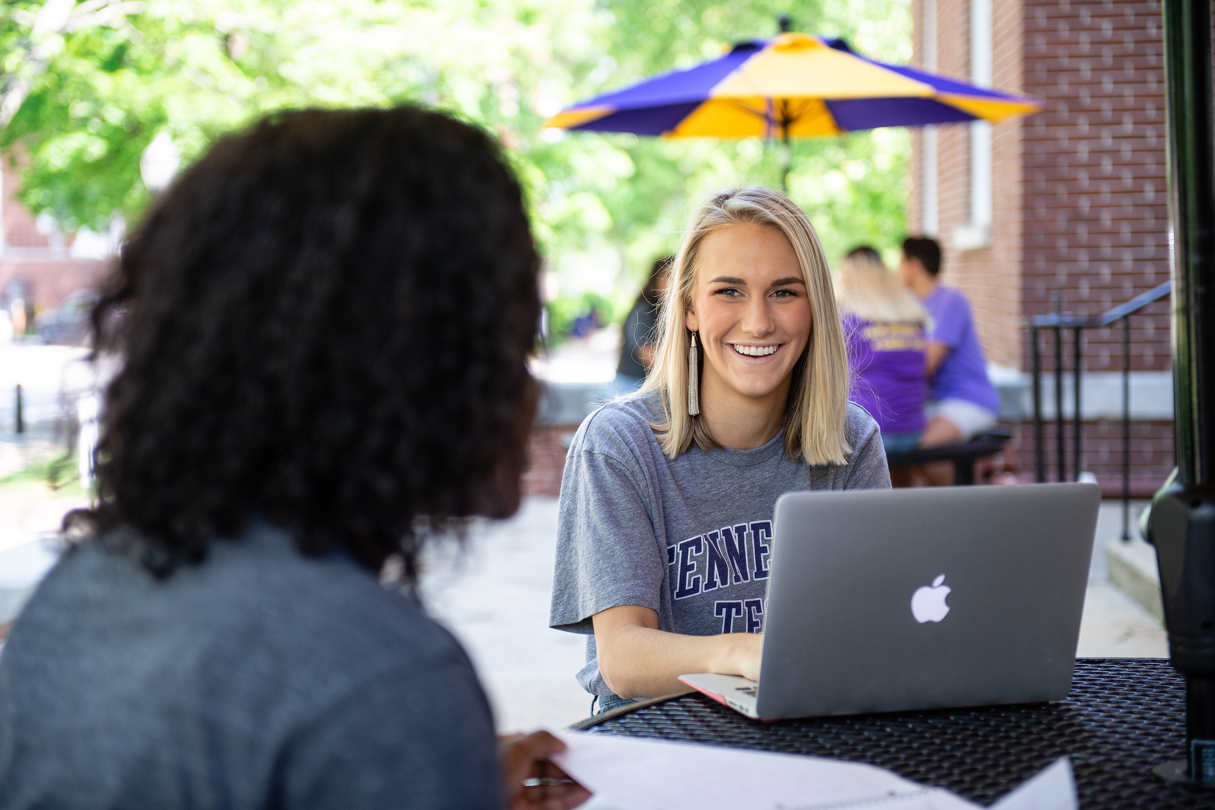 A student smiling and working on a project with another student