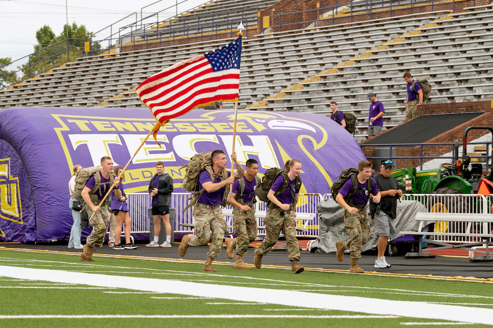 ROTC Cadets run with the American flag on Tennessee Tech's football field.