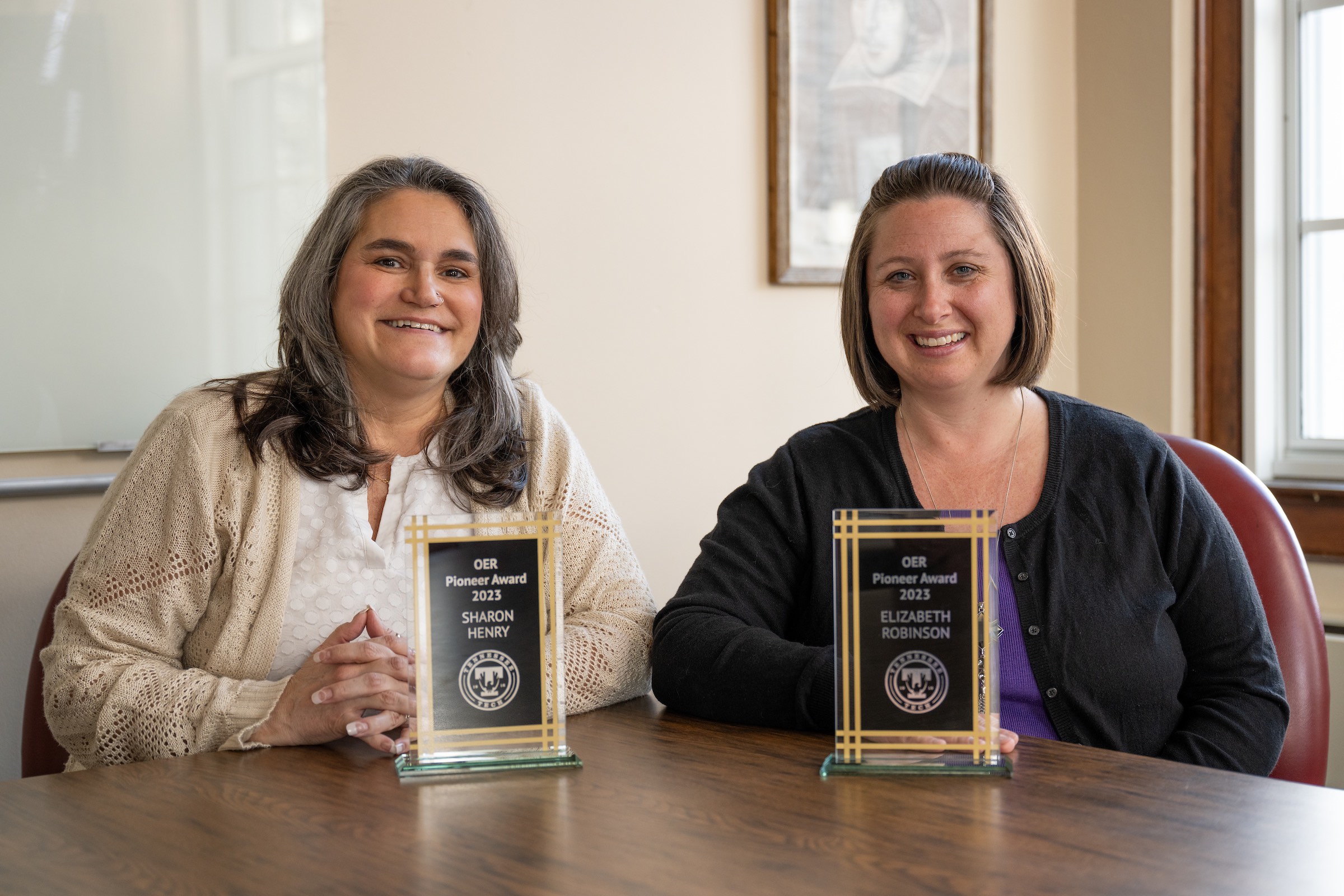 From left: Tech senior lecturer Sharon Henry and senior instructor Elizabeth Robinson hold their 2023 “OER Pioneer Award” for their leadership in developing zero-cost course materials.