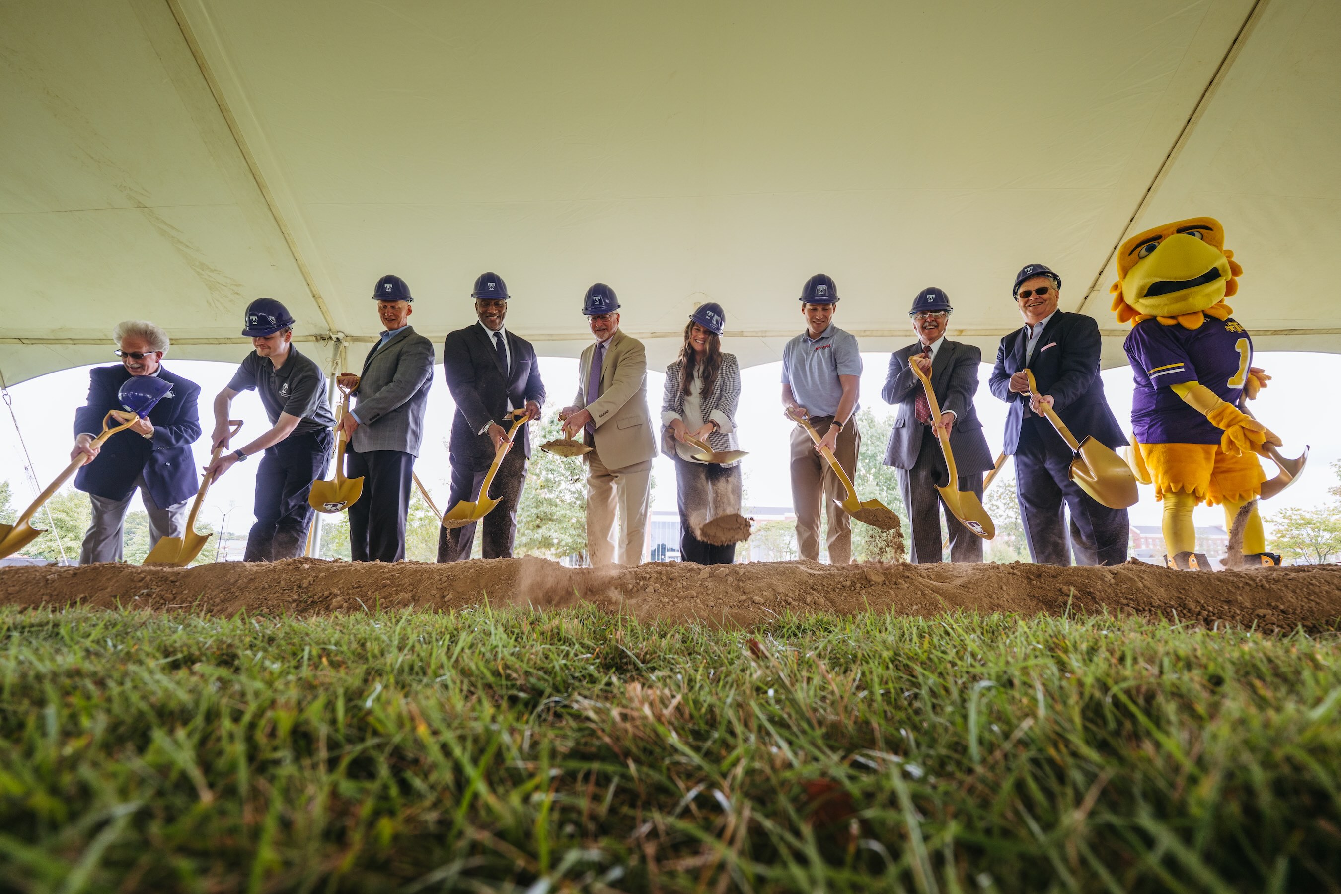 University leaders wear hard hats and hold shovels at the ceremonial groundbreaking.