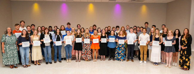 student scholarship recipients stand with certificates smiling with members of the Parent Association's Board of Trustees