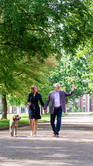 President Oldham and Frist Lady walk down the Main Quad waving to students.