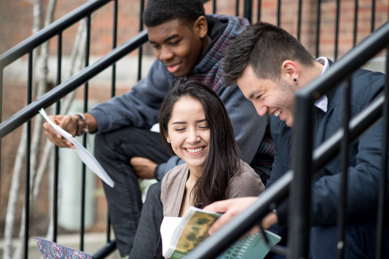 three students sitting on steps studying together