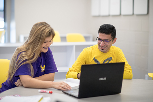 Students sitting at a table with a computer