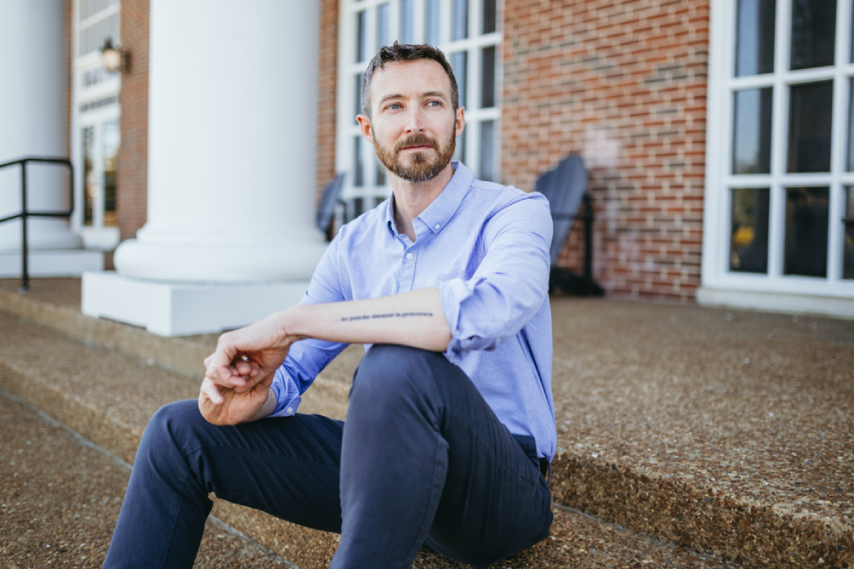 Joshua Martin sits on the steps outside a campus building.