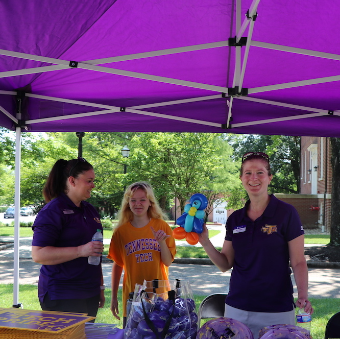 Brooke Fleenor, her daughter, and Kelly Chambers stand behind the Crawford Alumni Center table at the event. 