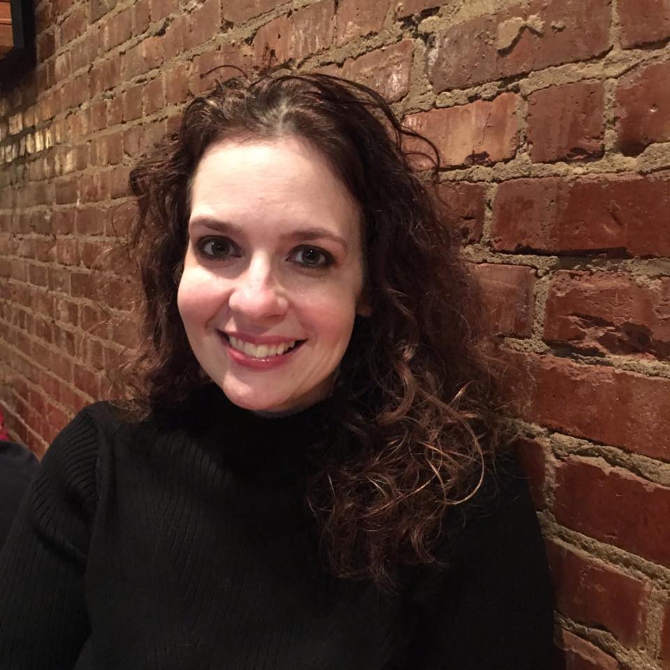 A portrait of Kathleen Lordo. There is a brick wall behind her.