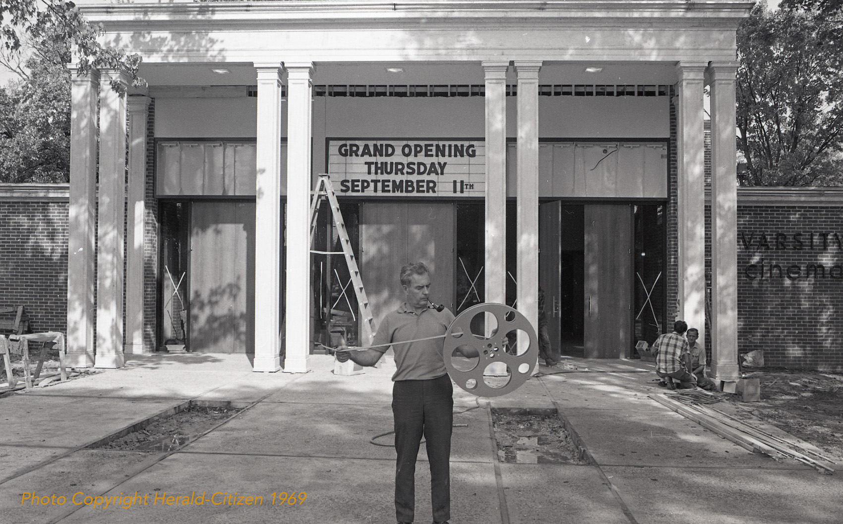 Varsity Theater with Mr. Delozier standing in front with a film reel in 1969.