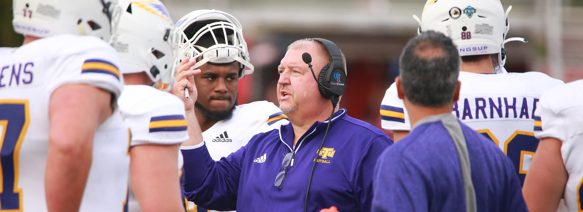 Coach Alexander speaks to members of the football team on the field