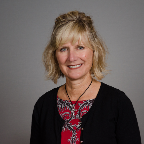 Portrait of Stephanie Dedmon. She has shoulder-length blonde hair and is wearing a red blouse and black cardigan.