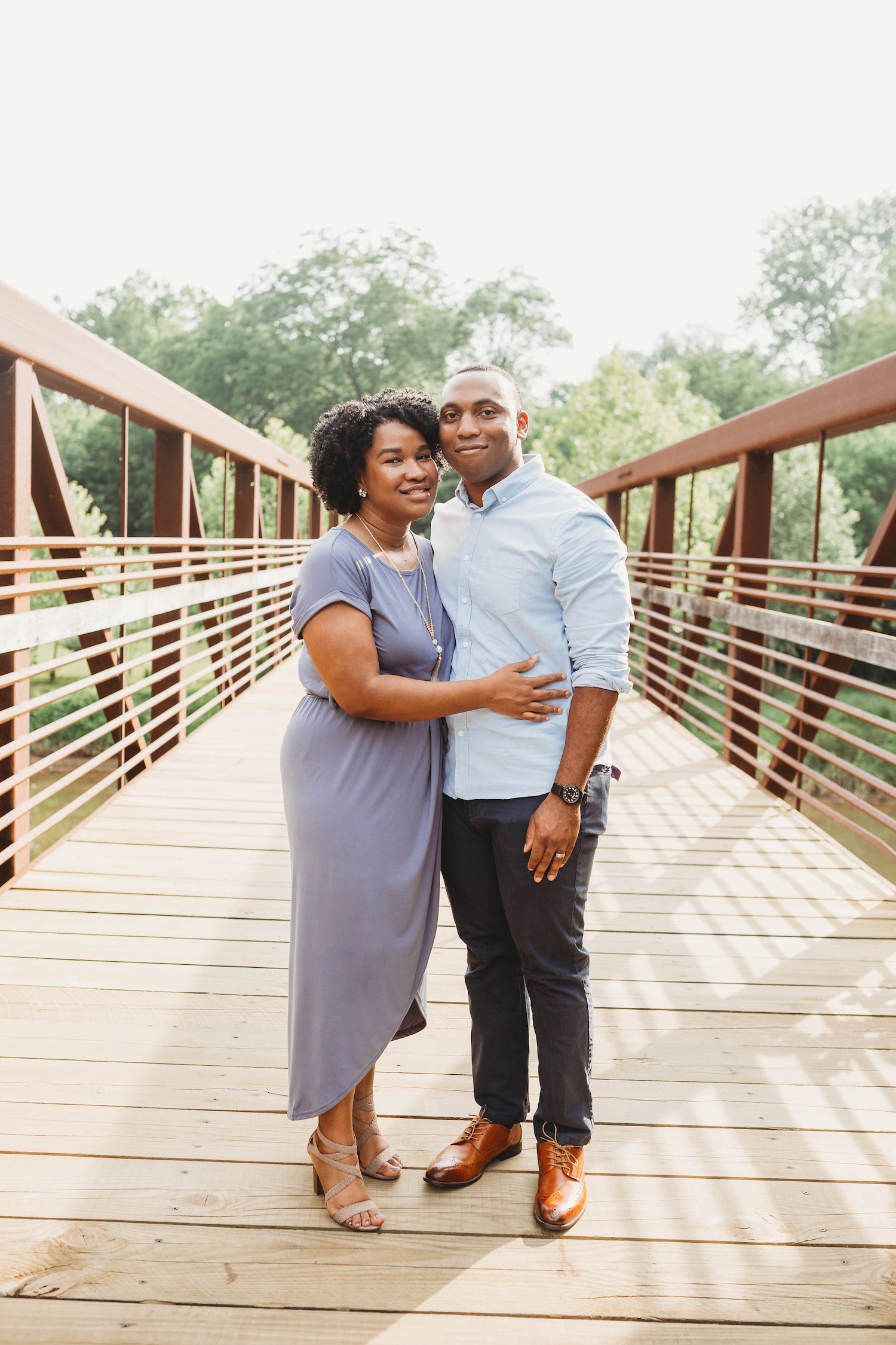 A photo of Jilandra and Kaelin holding each other and standing on a wooden bridge"