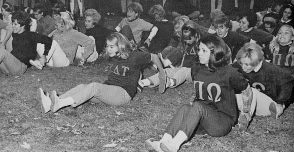 Sorority particpating in game where they are sitting on the ground and holding onto the feel of the person behind them.