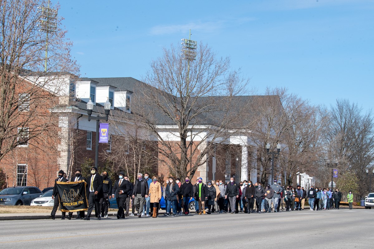 members of Alpha Phi Alpha marching down Dixie Ave. in front of the RUC