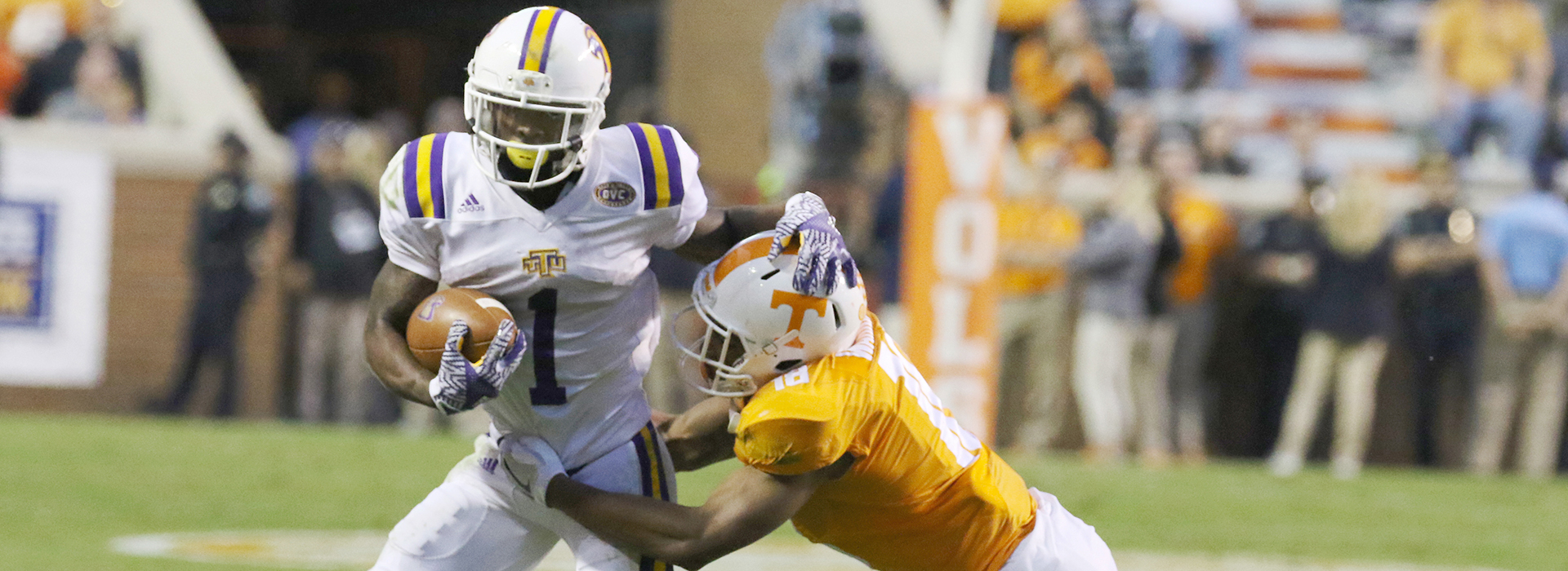 An action photo of a Tech football player holding off a UT football player on the field.