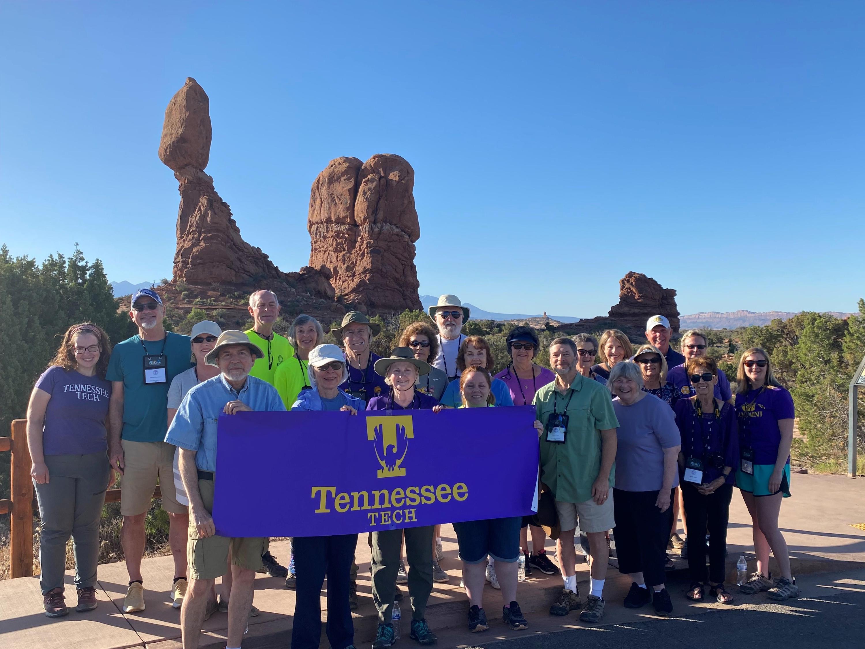 A group of alumni hold a Tennessee Tech banner in front of balancing rock at Arches National Park