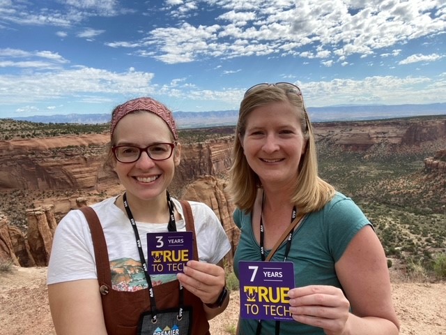 Two women stand at an overlook at Canyonlands with their True To Tech magnets.