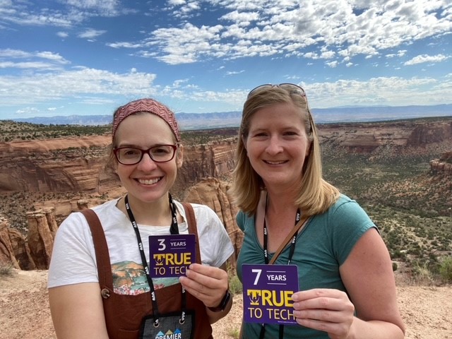 Two women stand at an overlook at Canyonlands with their True To Tech magnets.